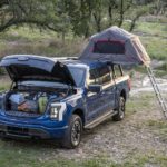 A blue 2022 Ford F-150 Lightning is shown set up for camping.