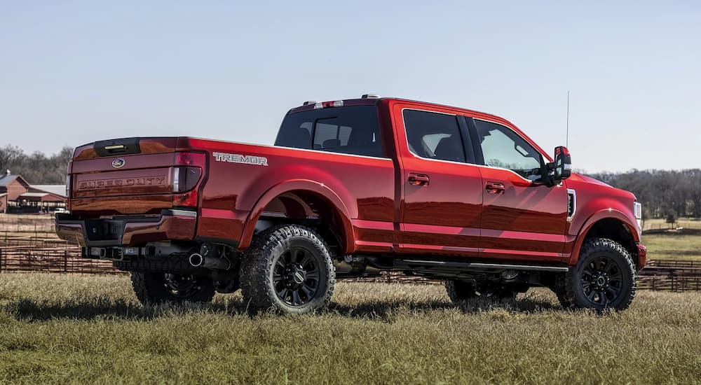 A red 2022 Ford F-250 Super Duty Lariat Tremor is shown from the side parked on grass.