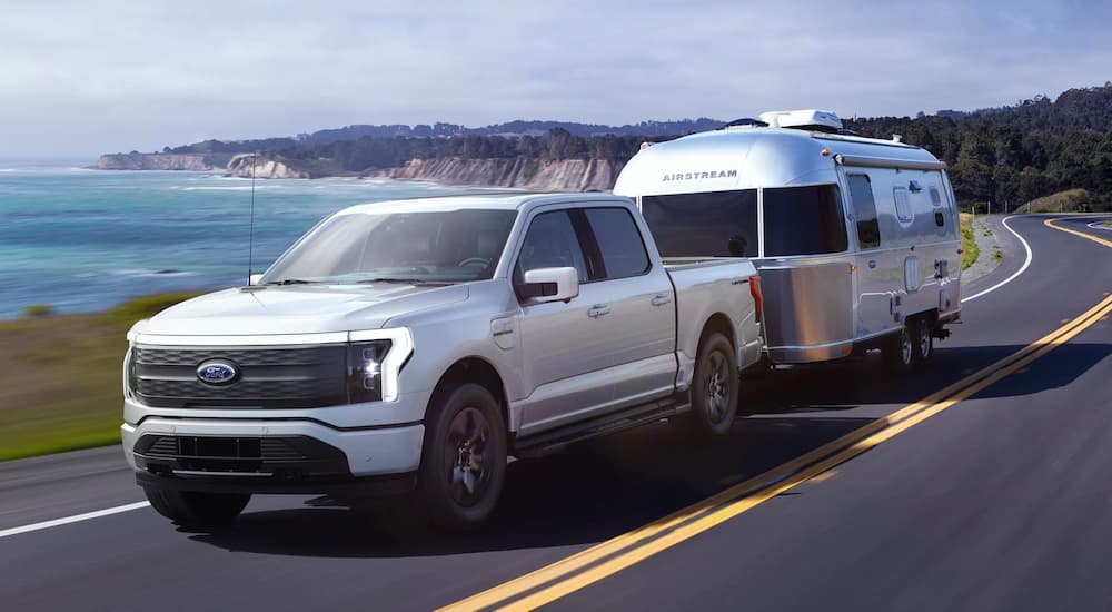 A silver 2022 Ford F-150 is shown towing a camper trailer.