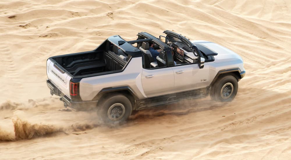 A 2022 GMC Hummer EV Pickup is shown from a high angle while it drives through sand.