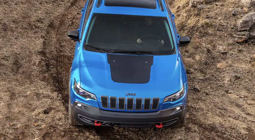 A blue 2022 Jeep Cherokee Trailhawk is shown off-roading.