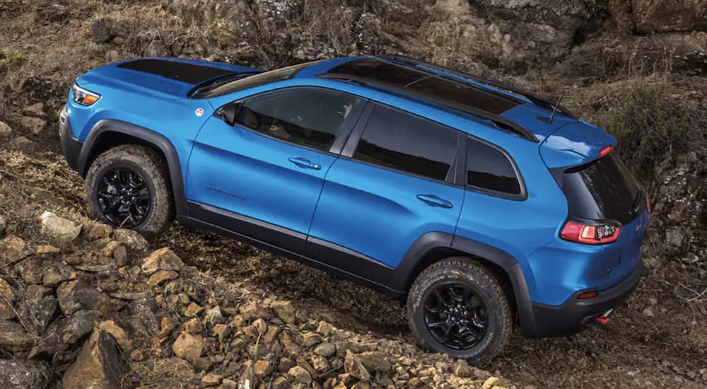 A blue 2022 Jeep Cherokee Trailhawk is shown from the side off-roading after leaving a Jeep dealer.