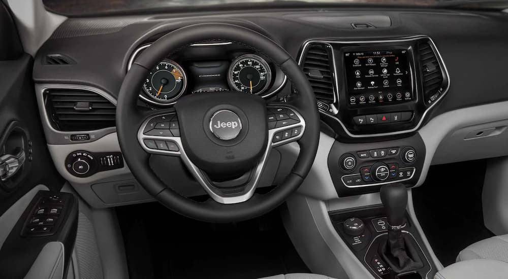 The black interior of a 2022 Jeep Cherokee Trailhawk shows off the steering wheel and infotainment screen.