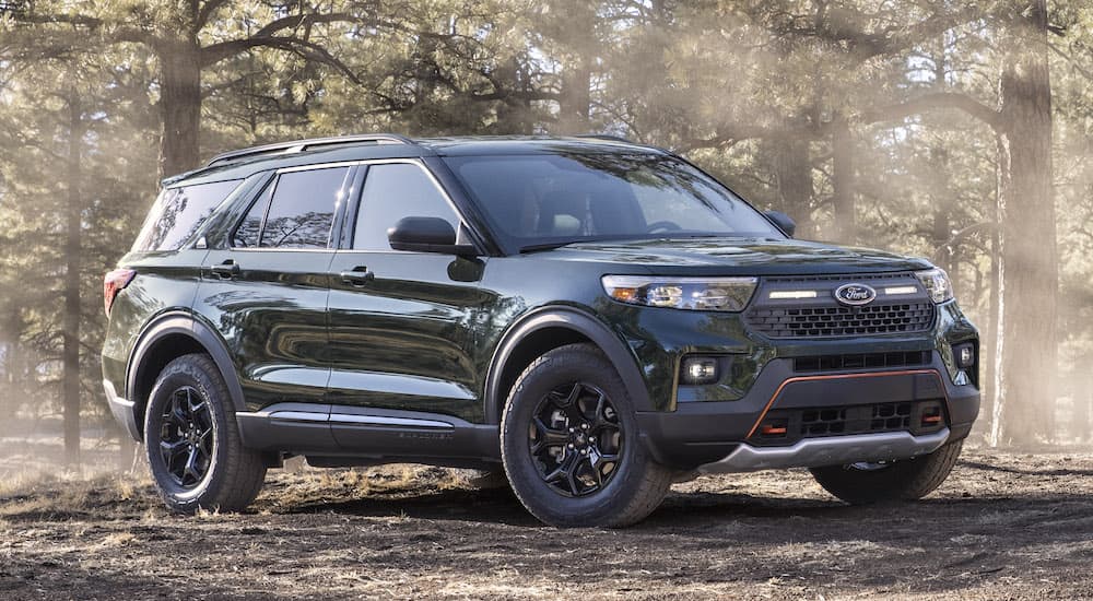 A green 2021 Ford Explorer Timberline is shown from the front at an angle while parked in a forest.