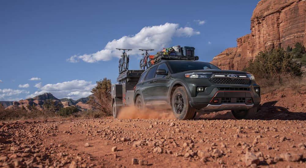 A green 2022 Ford Explorer Timberline is shown from the front while towing a trailer off-road.