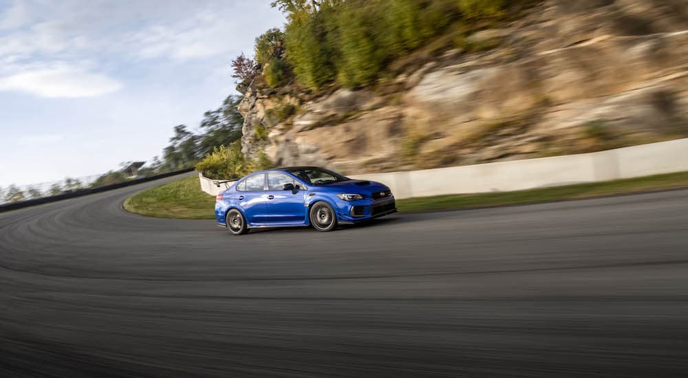 A blue 2019 Subaru WRX STI S209 is shown from the side while cornering at speed.