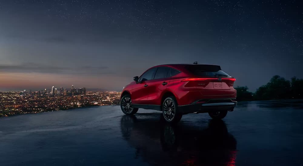 A red 2022 Toyota Venza Nightshade Edition is shown overlooking a city at night.