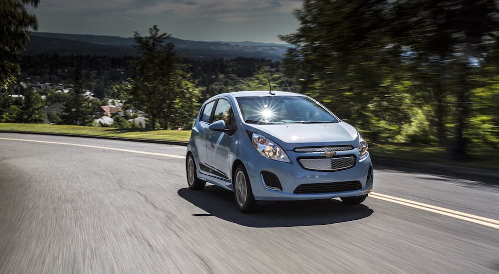 A light blue 2016 Chevy Spark EV is shown on a highway after visiting a used Chevy dealership.