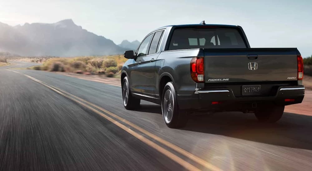 A grey 2020 Honda Ridgeline RTL-E is shown driving on an open road. 