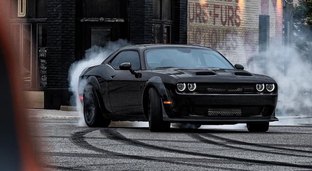 A black 2023 Dodge Challenger Hellcat Redeye is shown from the front at an angle while performing a burnout.