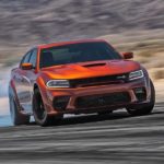 An orange 2023 Dodge Challenger Scat Pack Wide Body is shown from the front while drifting.