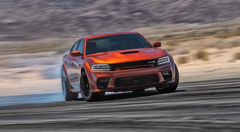 An orange 2023 Dodge Challenger Scat Pack Wide Body is shown from the front while drifting.