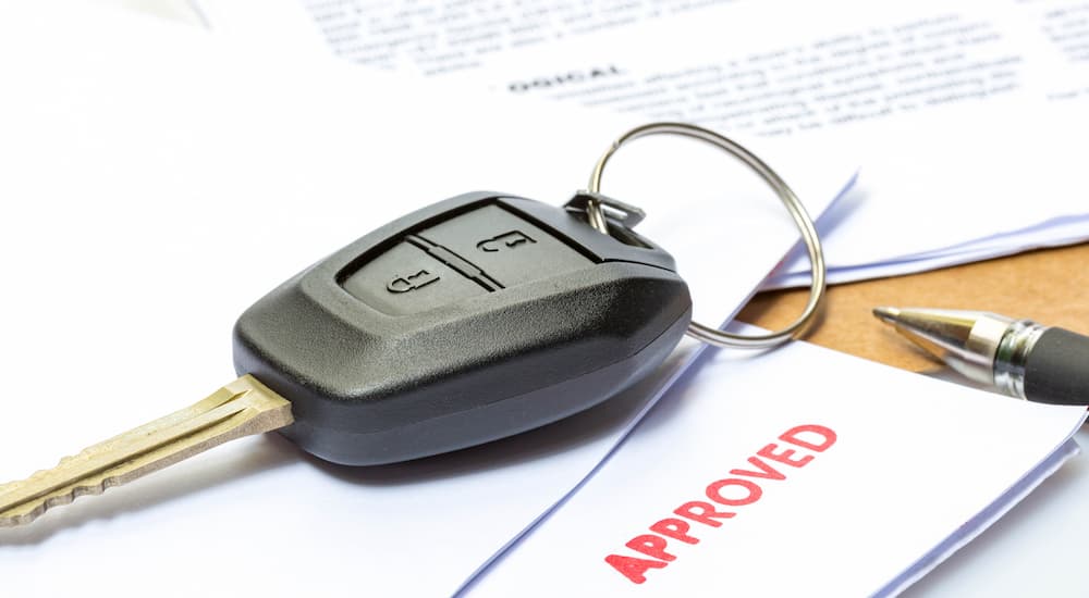 A close up of a key is shown on used car financing paperwork.