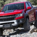 A red 2019 Chevy Colorado Bison is shown from the front while driving over rocks.