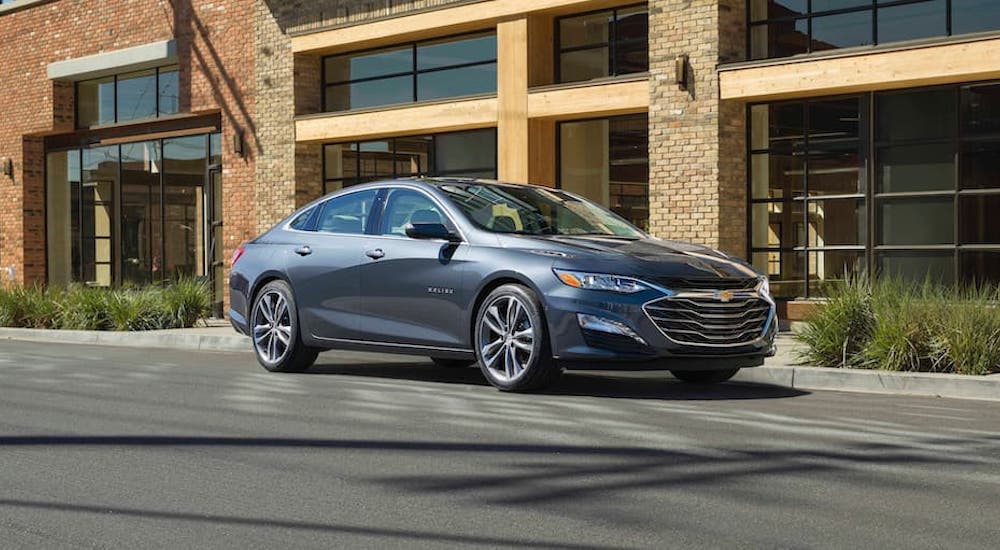 A grey 2022 Chevy Malibu is shown from the front at an angle on a city street.