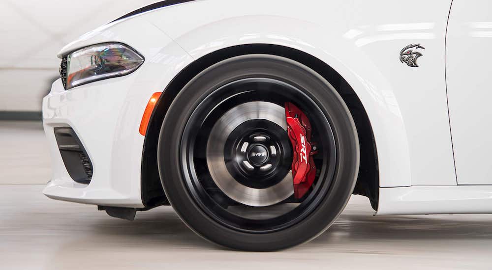 A close-up shows the wheel of a white 2022 Dodge Charger SRT Hellcat Redeye.