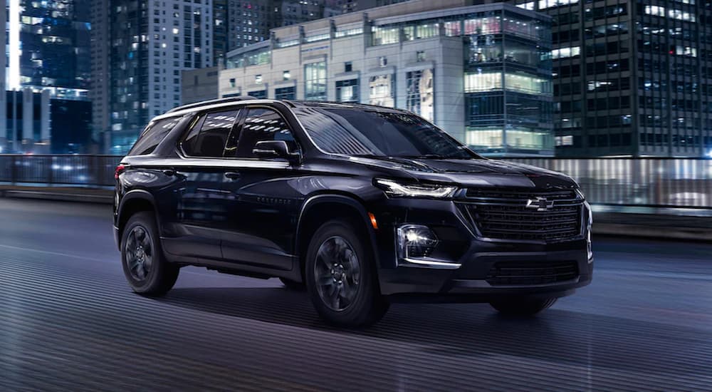 A black 2023 Chevy Traverse Midnight Edition is shown driving on a city street.