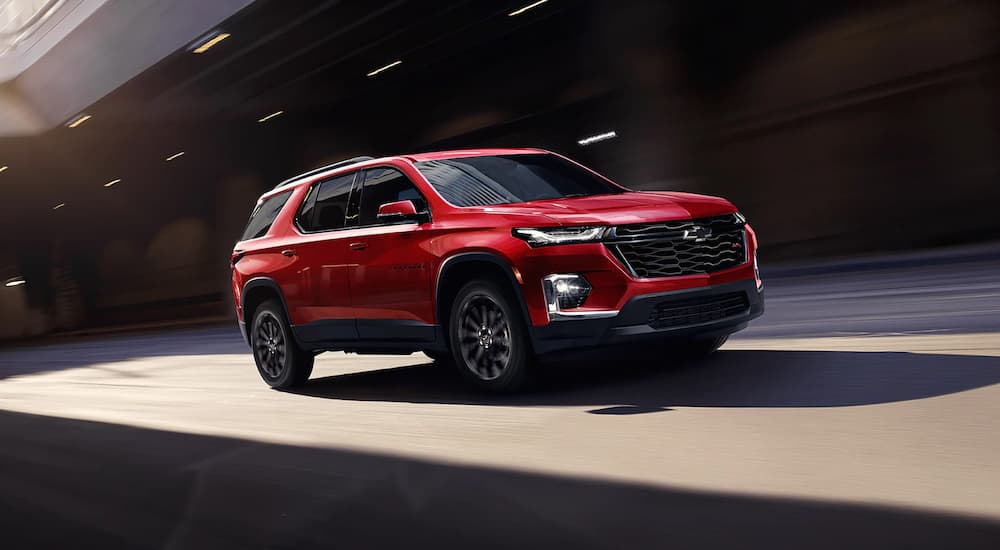 A red 2023 Chevy Traverse RS is shown driving on an underpass.