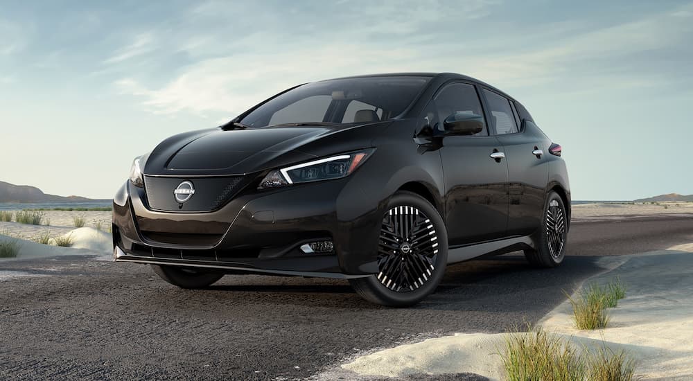 A black 2023 Nissan LEAF is shown parked on a sandy path.