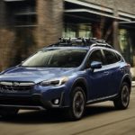 A blue 2023 Subaru Crosstrek is shown from the front at an angle on a city street.