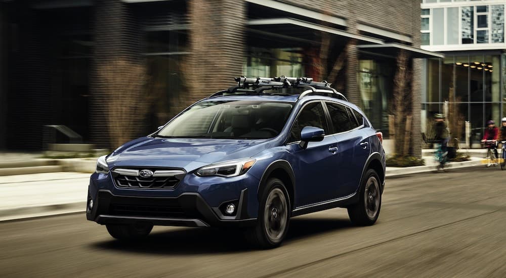 A blue 2023 Subaru Crosstrek is shown from the front at an angle on a city street.