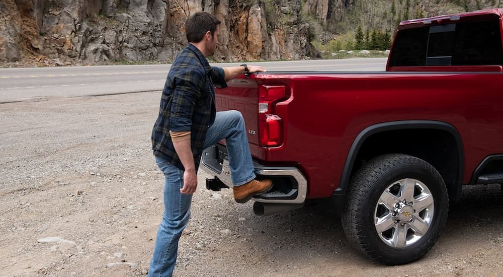 A man is shown stepping up into the bed of a red 2022 Chevy Silverado 1500.