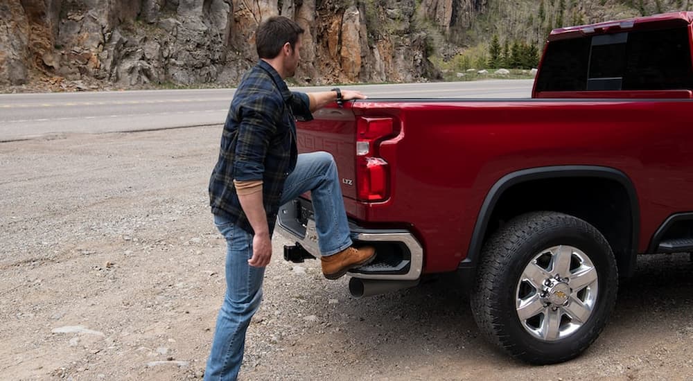 A man is shown stepping up into the bed of a red 2022 Chevy Silverado 1500.