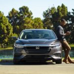 A man is shown leaning against a grey 2022 Honda Insight.