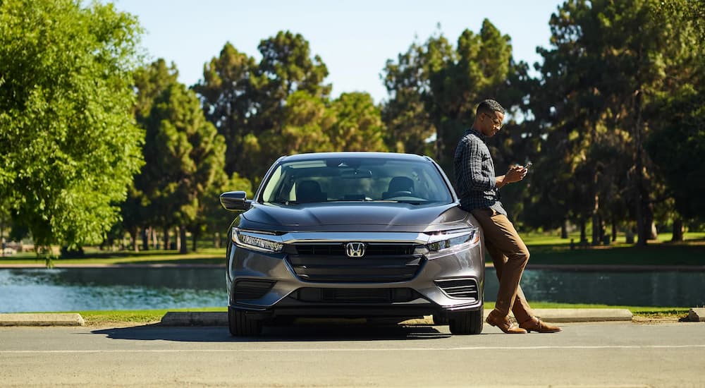 A man is shown leaning against a grey 2022 Honda Insight.