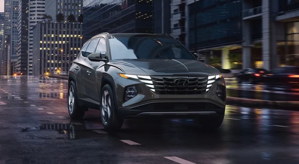 A grey 2023 Hyundai Tuscon is shown driving on a city street.