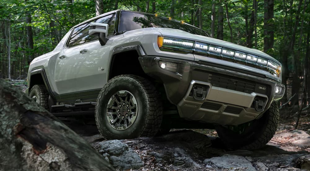 A grey GMC Hummer EV is shown from the front while driving off-road.