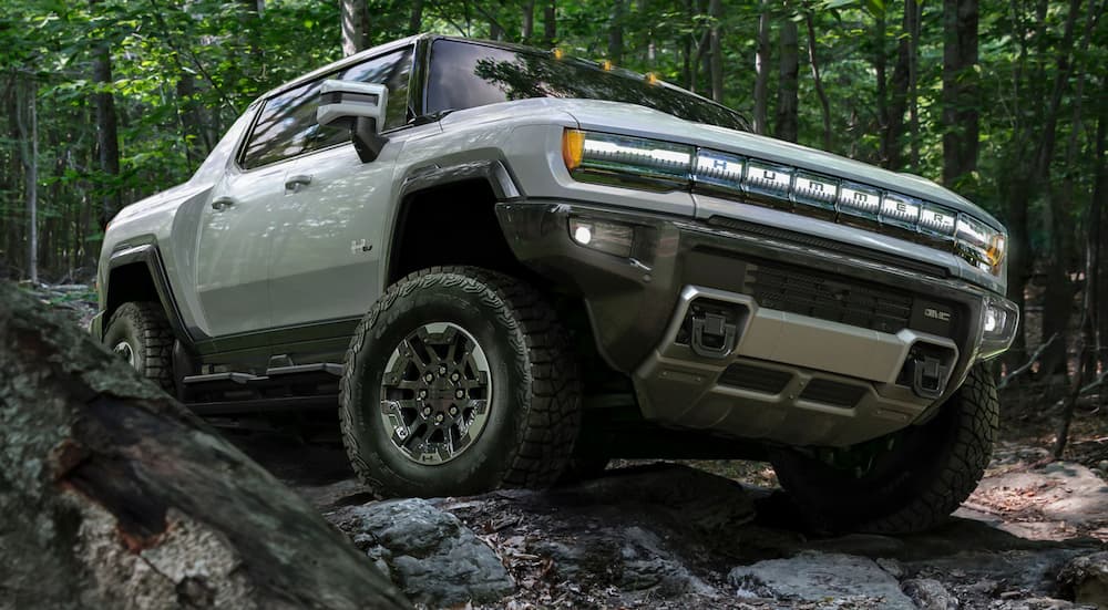 A green 2024 GMC Hummer EV is shown from the front while driving off-road.