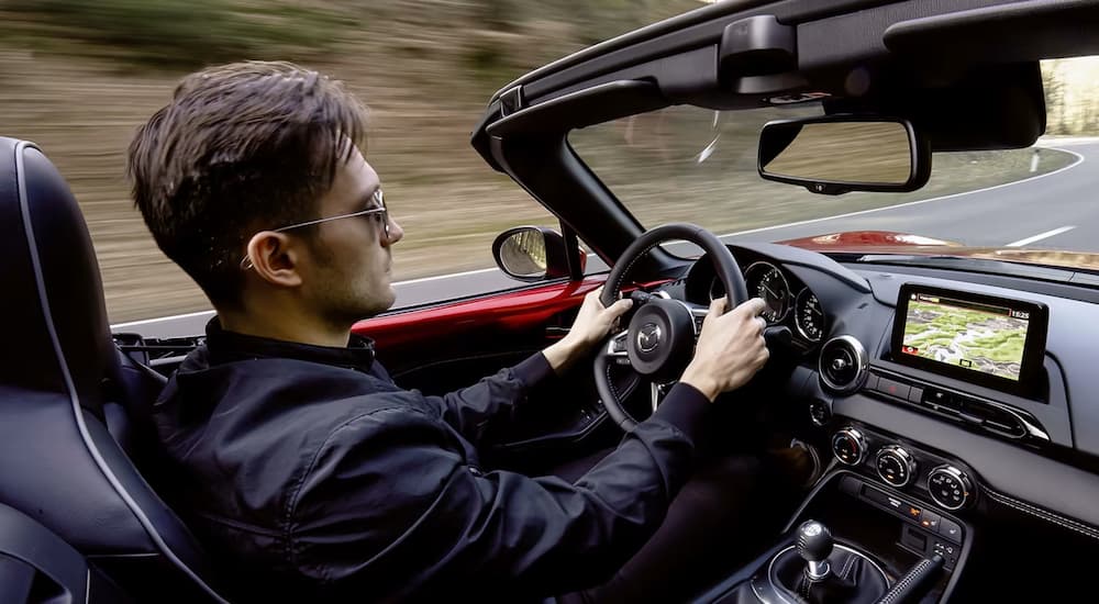 A person is shown driving a red 2023 Mazda MX-5 Miata after visiting a Mazda dealer.