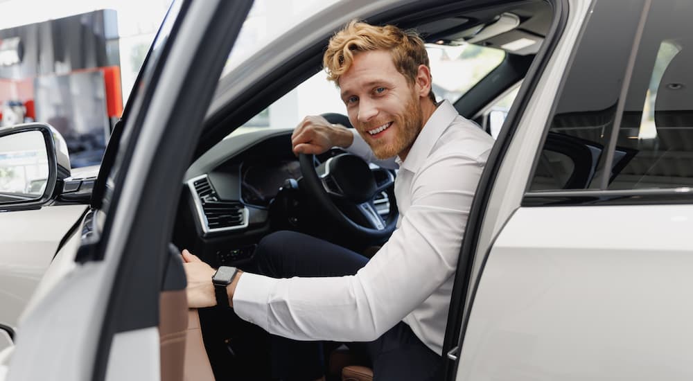 A man is shown opening the door of a white vehicle.