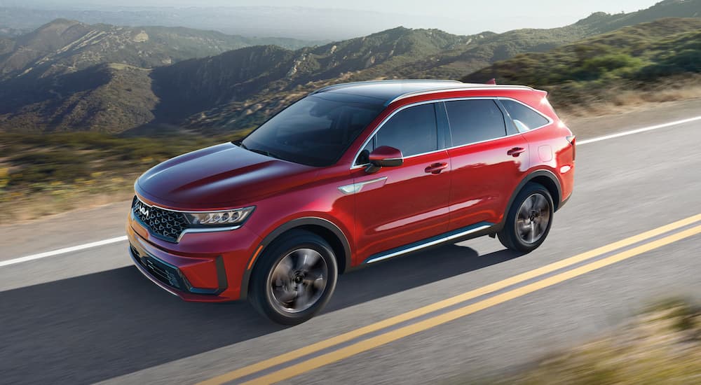 A red 2022 Kia Sorento Hybrid is shown driving on a mountain road.