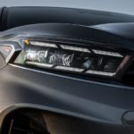 A close up of the headlight on a grey 2022 Kia Forte is shown at a car dealership.
