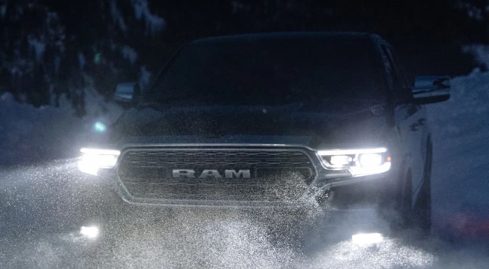 A black 2022 Ram 1500 is shown from the front while driving through snow after leaving a Ram dealer.