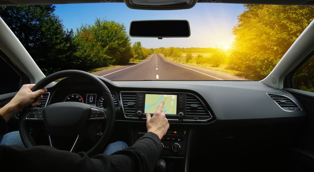 A person is shown driving a car on an open road.