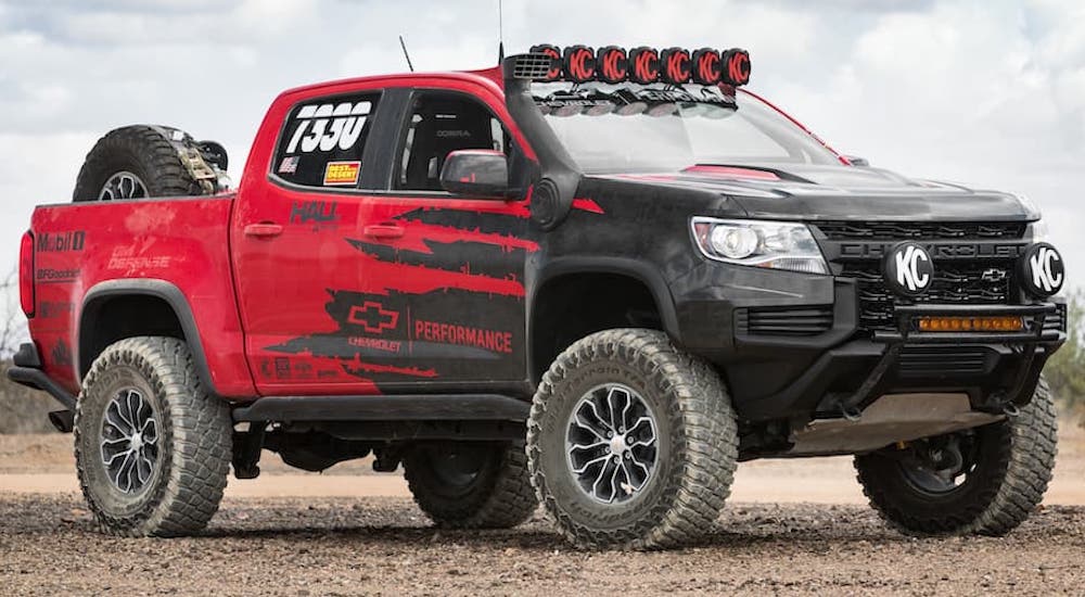 A red 2021 Chevy Colorado ZR2 race truck is shown from the side while parked off-road.