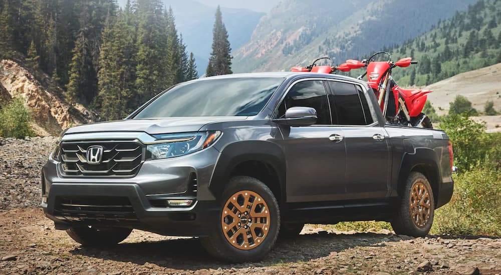 A grey 2023 Honda Ridgeline is shown from the front at an angle while loaded with dirt-bikes.