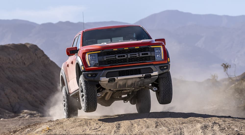 A red 2022 Ford F-150 Raptor is shown from the front while jumping after leaving a Ford dealer..