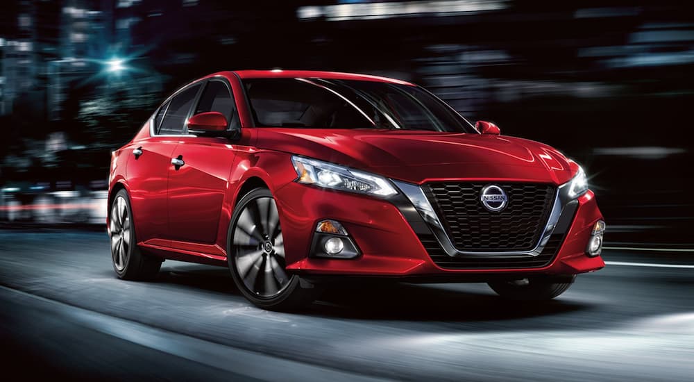 A red 2022 Nissan Altima is shown driving at night.