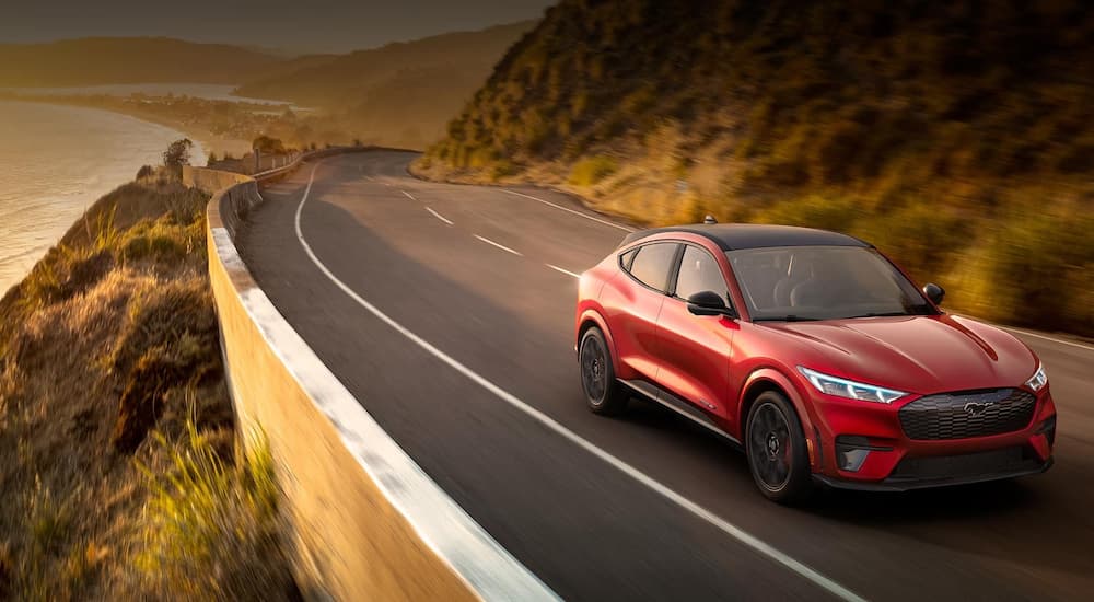 A red 2022 Ford Mustang Mach-E is shown driving on a coastal highway after winning a 2022 Ford Mach-E vs 2022 Tesla Model Y showdown.