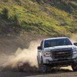 A white 2021 GMC Canyon AT4 is shown from the front after leaving a dealer that had used lifted trucks for sale.