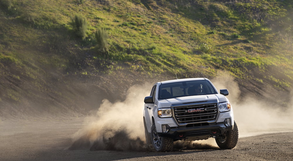 A white 2021 GMC Canyon AT4 is shown from the front after leaving a dealer that had used lifted trucks for sale.