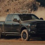 A black 2022 Ram 2500 Cummins is shown kicking up dirt off-road.