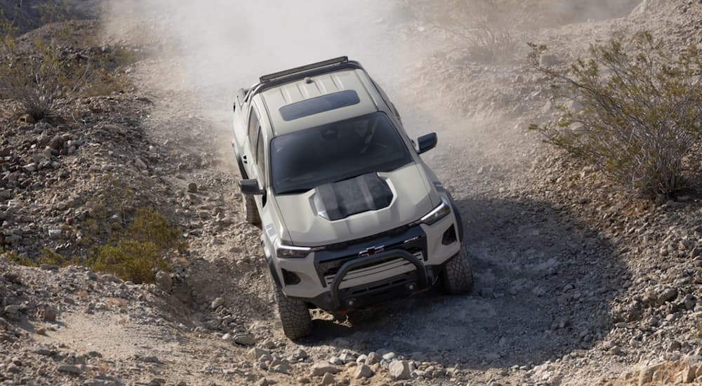 A tan 2023 Chevy Colorado is shown off-roading on a dirt road.