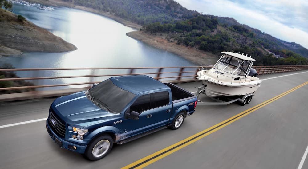 A blue 2017 Ford F-150 XLT is shown towing a boat.