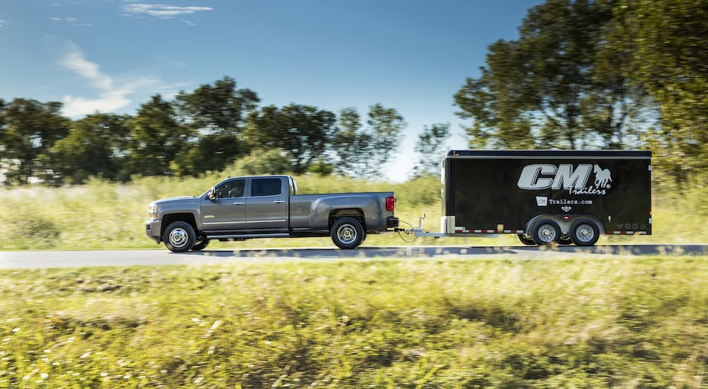 A gray 2017 Chevy Silverado 3500HD High Country is shown towing a black trailer.