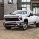 A white 2024 Chevy Silverado 3500HD LTZ is shown in front of a house being built.